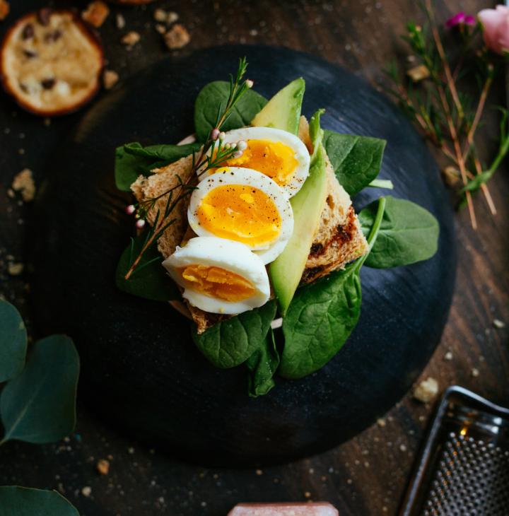 A palte of spinach with toast, 
                avocado and eggs present as art
